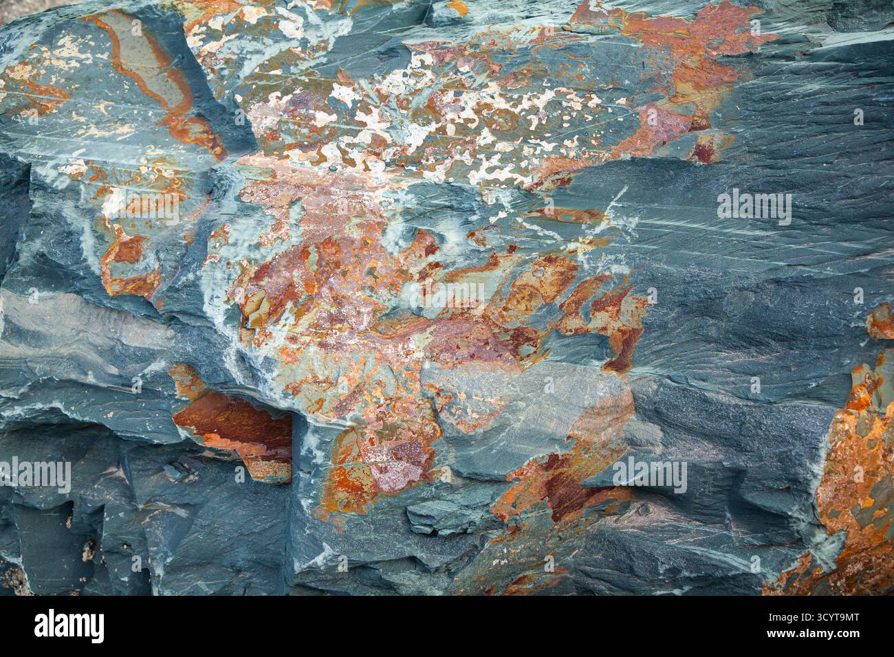 The texture of natural stone with an uneven surface and multi-colored inclusions Stock Photo
