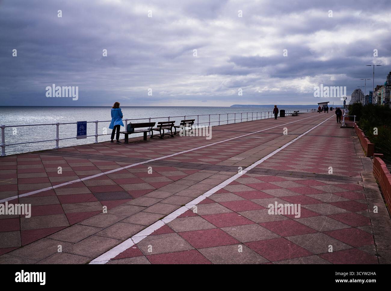 Lone women looking at smartphone on prom at Hastings Stock Photo