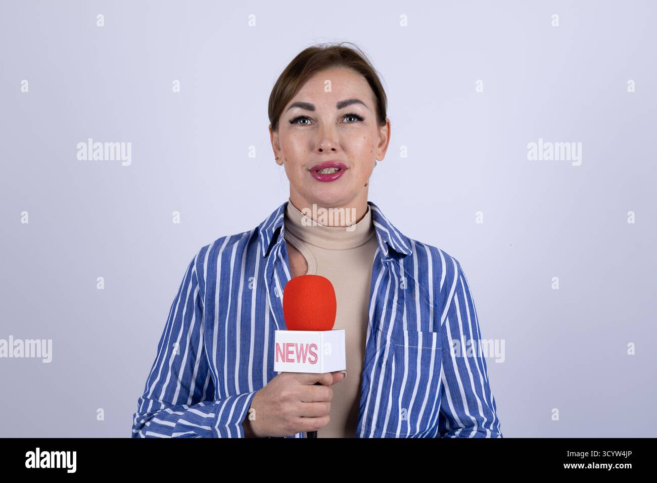 The news reporter is holding a microphone and preparing to deliver a ...