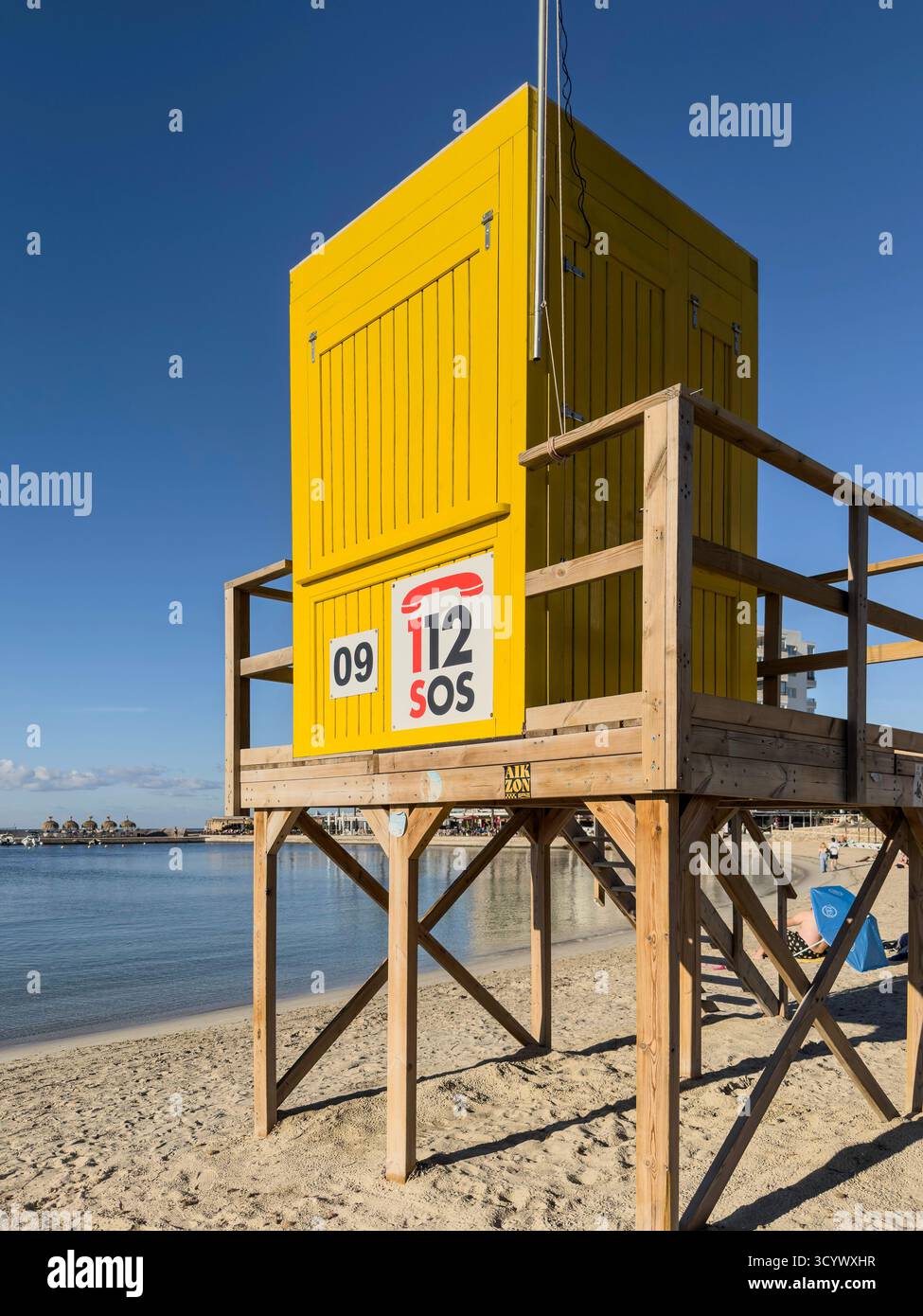 A yellow lifeguard station hut  on a wooden platform stands on a beach by the calm sea under a clear blue sky C'an pastilla mallorca - Smartphone Captured Stock Image