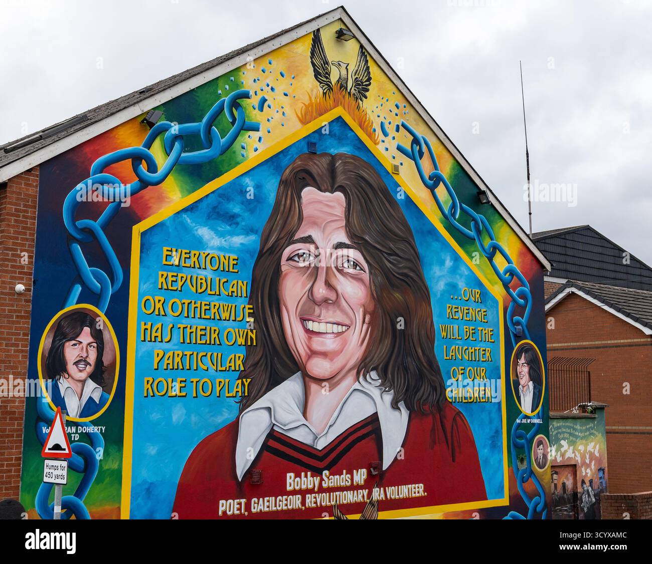 Colorful mural tribute to Bobby Sands on a gable wall in Falls Road Belfast, featuring his portrait and political quotes with bright symbolic imagery Stock Photo