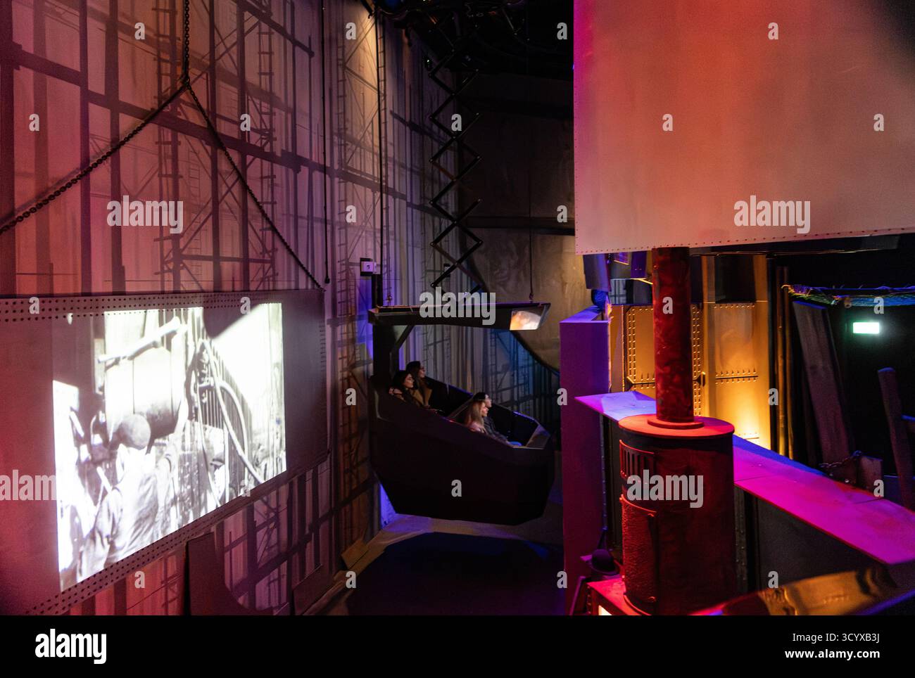 Visitors experiencing the interactive historical Titanic ship simulator with projected black and white footage inside a museum exhibit in Belfast Stock Photo