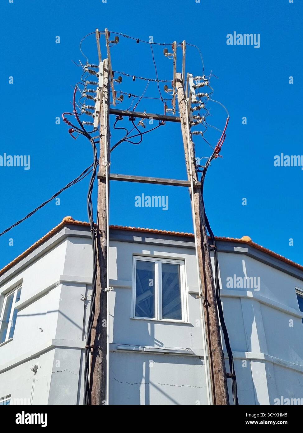 A three-phase high-voltage switchgear on wooden poles mounted on a building Stock Photo
