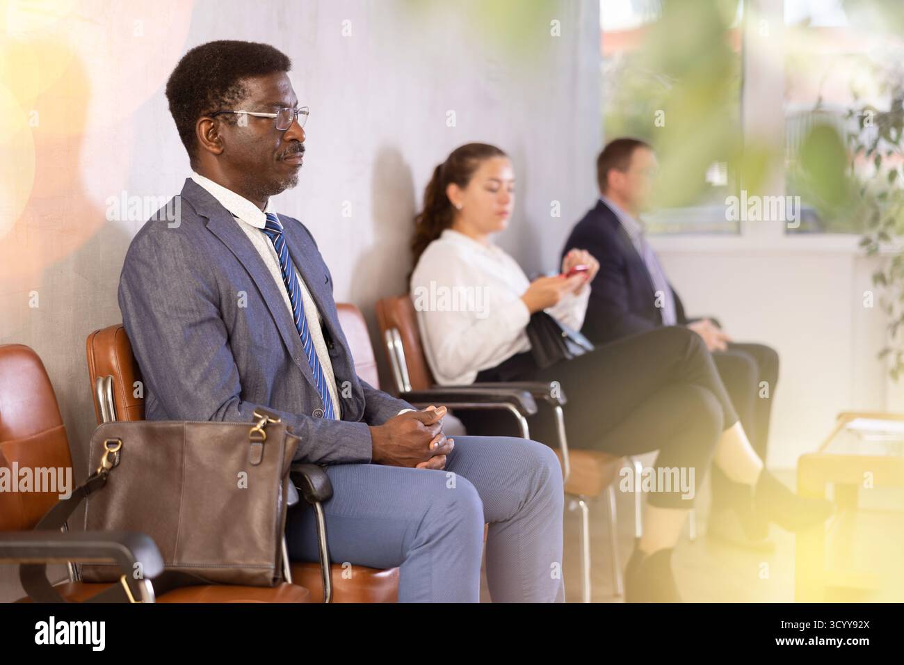 Serious-minded African male candidate siting on chair and waiting for ...