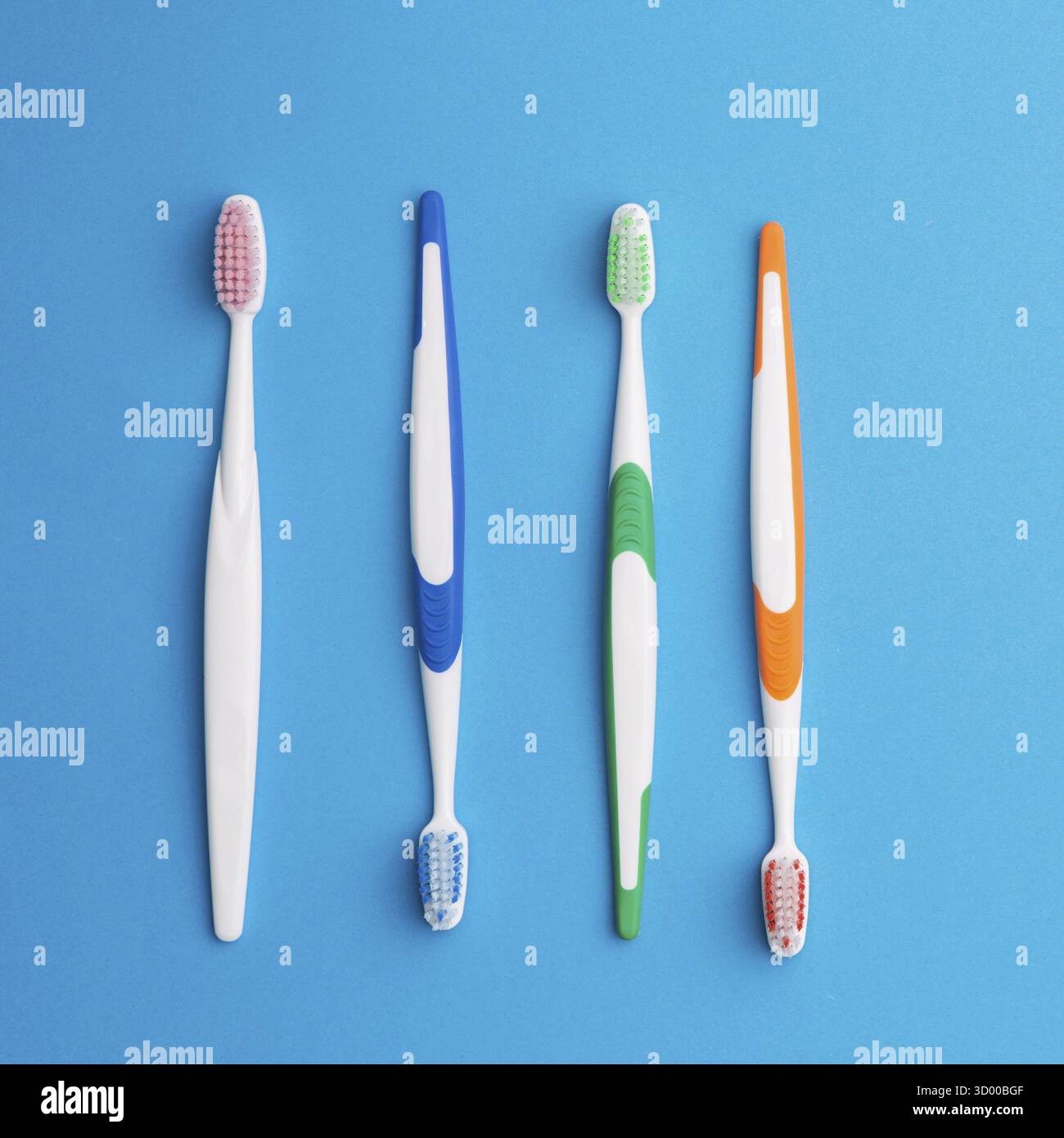 Four multicolored toothbrushes on empty blue background Stock Photo