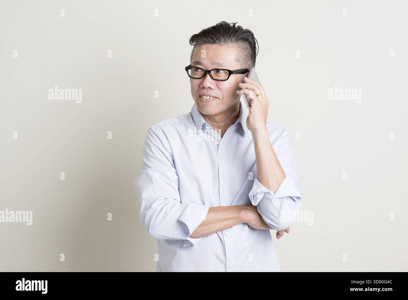 Portrait of single mature 50s Asian man in casual business calling on ...