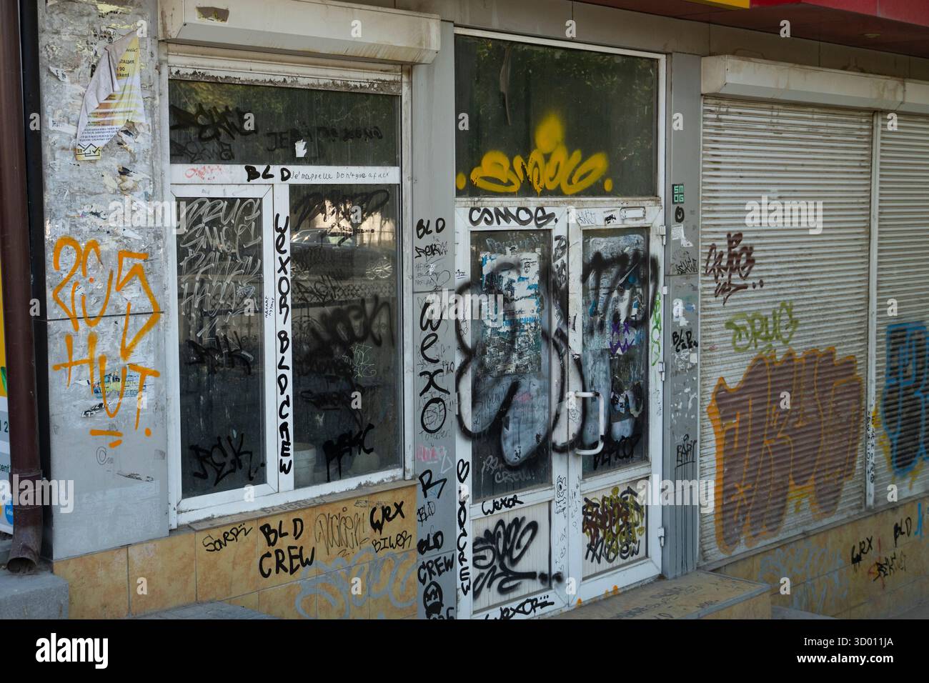 Shymkent, Kazakhstan, August 30, 2025: Urban facade with heavy graffiti on doors, windows, and walls, depicting street art, vandalism, and urban decay Stock Photo