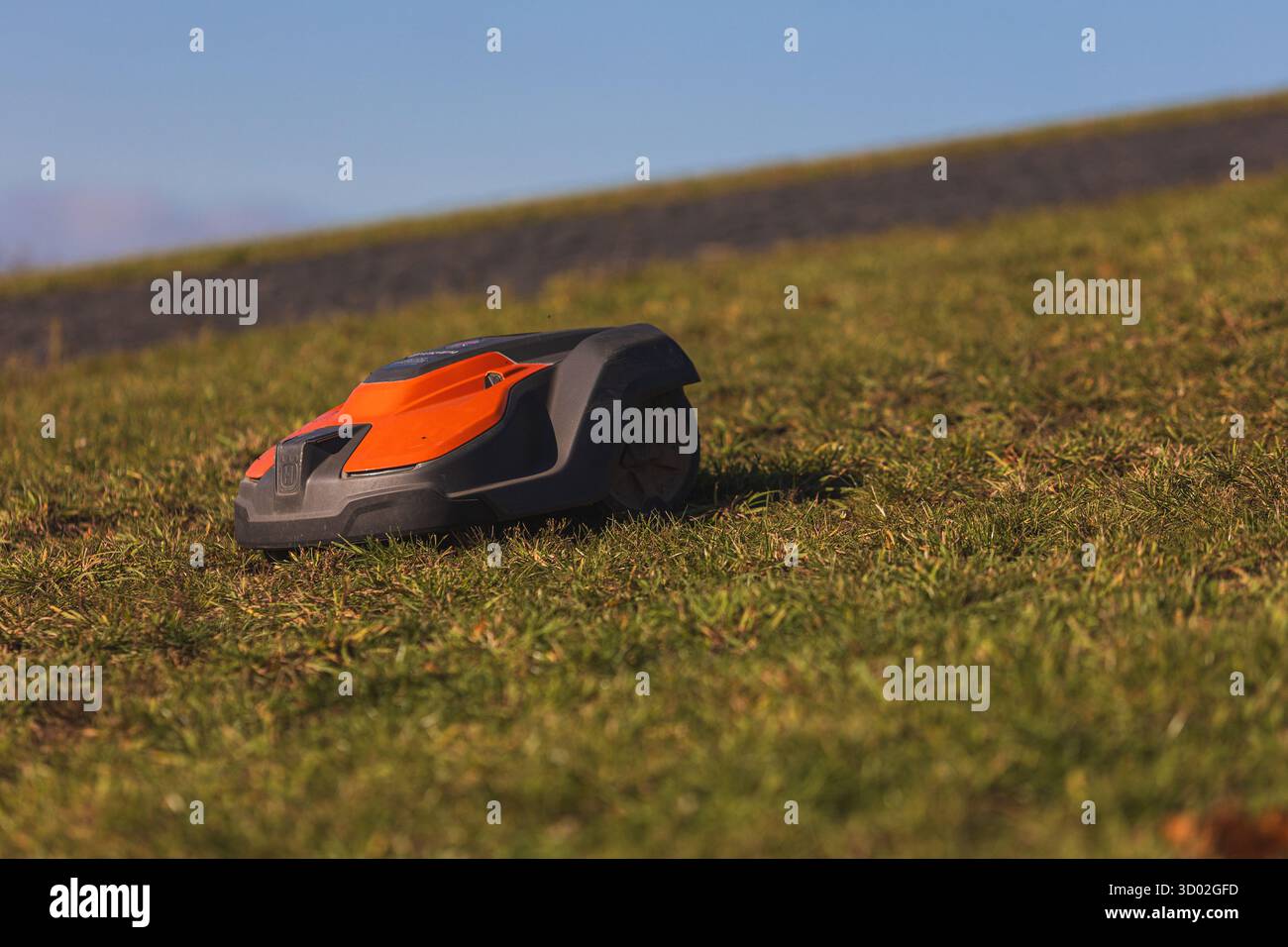Husqvarna robotic lawn mower stands ready to automatically trim a suburban green grass field. High quality photo Stock Photo