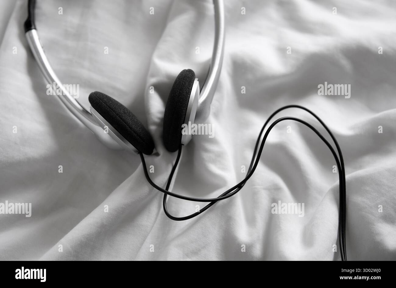 headphones on white crumpled bed sheet Stock Photo