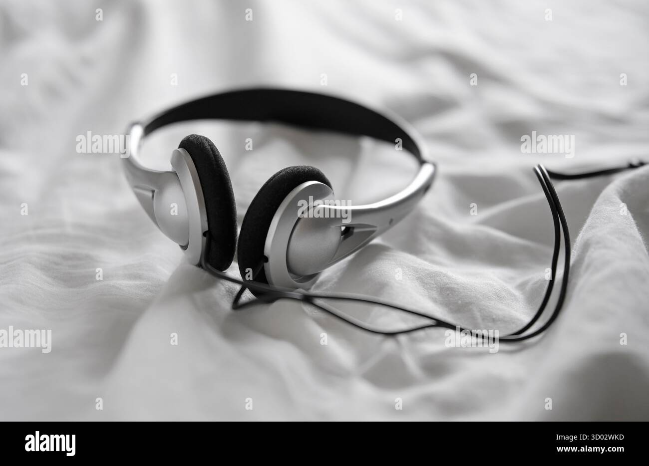 headphones on white crumpled bed sheet Stock Photo