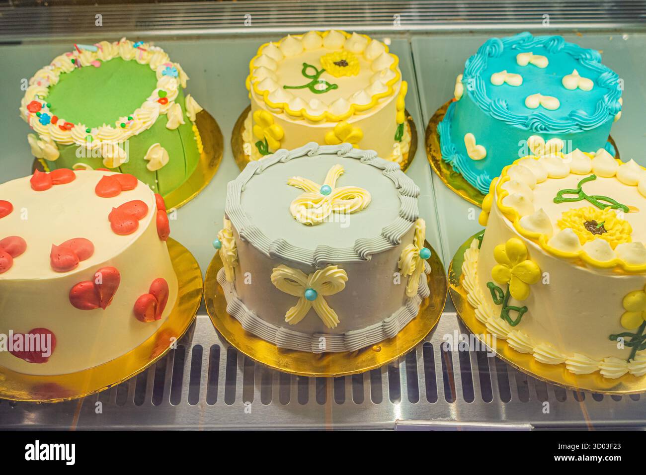Assorted cakes with intricate decorations are showcased in a bakery ...