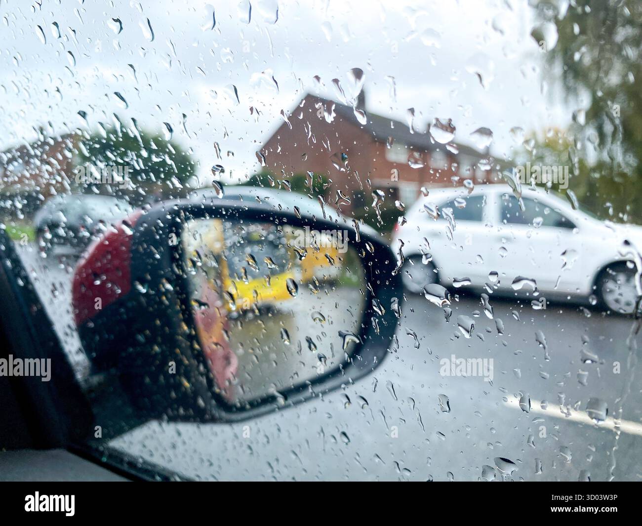 Looking at a car wing mirror through a side window which is covered in raindrops. - Smartphone Captured Stock Image