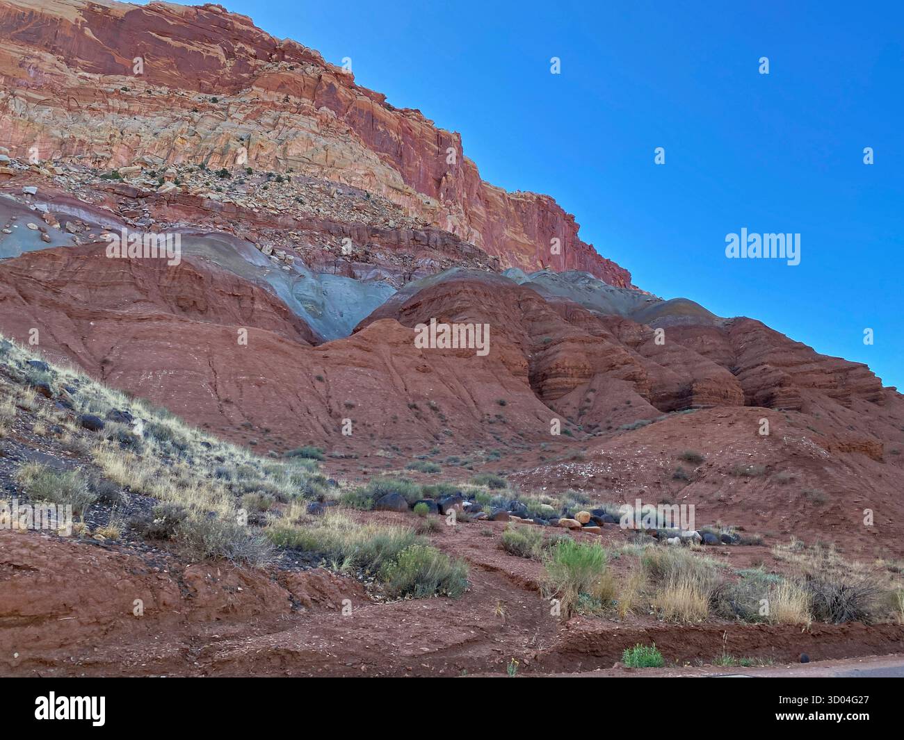 Eroding cliffs of red sandstone, shale and limestone, against a clear blue sky, lining Scenic Byway 24, in Capitol Reef National Park, Utah, USA - Smartphone Captured Stock Image