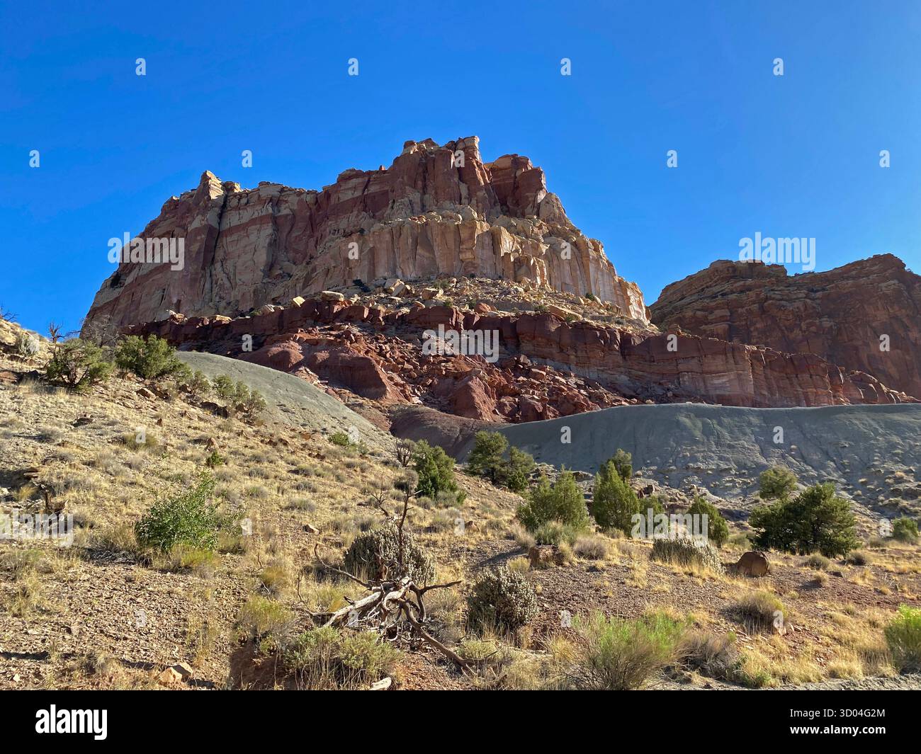 Eroding cliffs of red sandstone and limestone, against a clear blue sky, lining Scenic Byway 24, in Capitol Reef National Park, Utah, USA - Smartphone Captured Stock Image