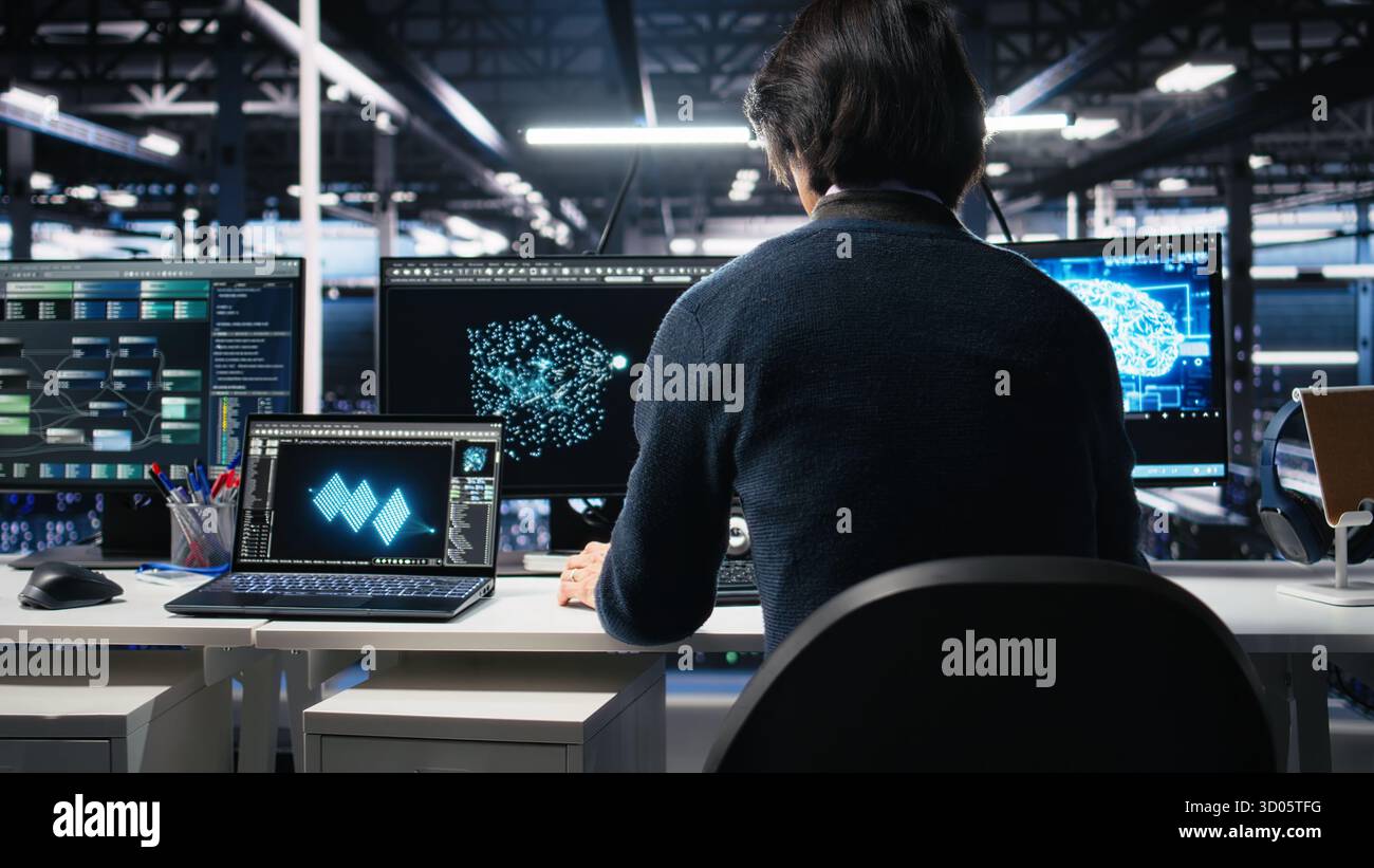 Admin entering data center office, reviews AI diagnostics on computer. IT expert starting work at server farm desk, optimizing artificial intelligence systems configuration, camera A Stock Photo