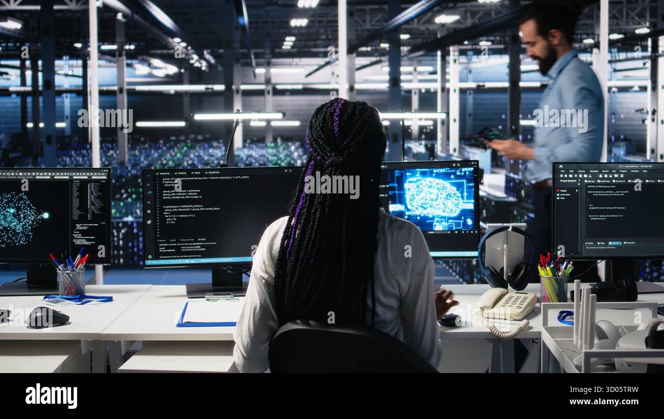 Female programmer in data center reviews AI diagnostics, analyzing neural network performance. Server hub IT expert optimizes artificial intelligence systems configuration, camera A Stock Photo