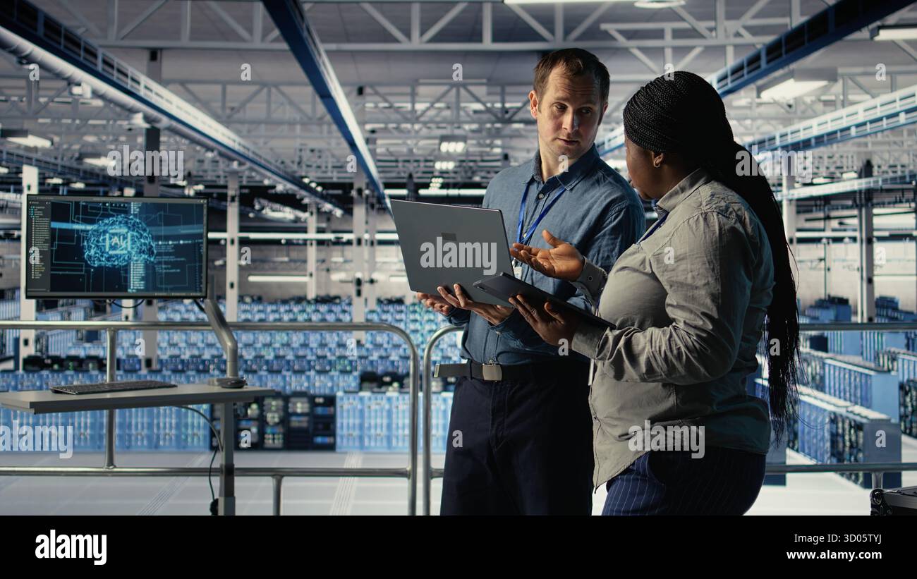 Technicians working together in server room, optimizing deep learning AI systems handling tasks. Data center coworkers doing brainstorming to adjust artificial intelligence model parameters, camera A Stock Photo
