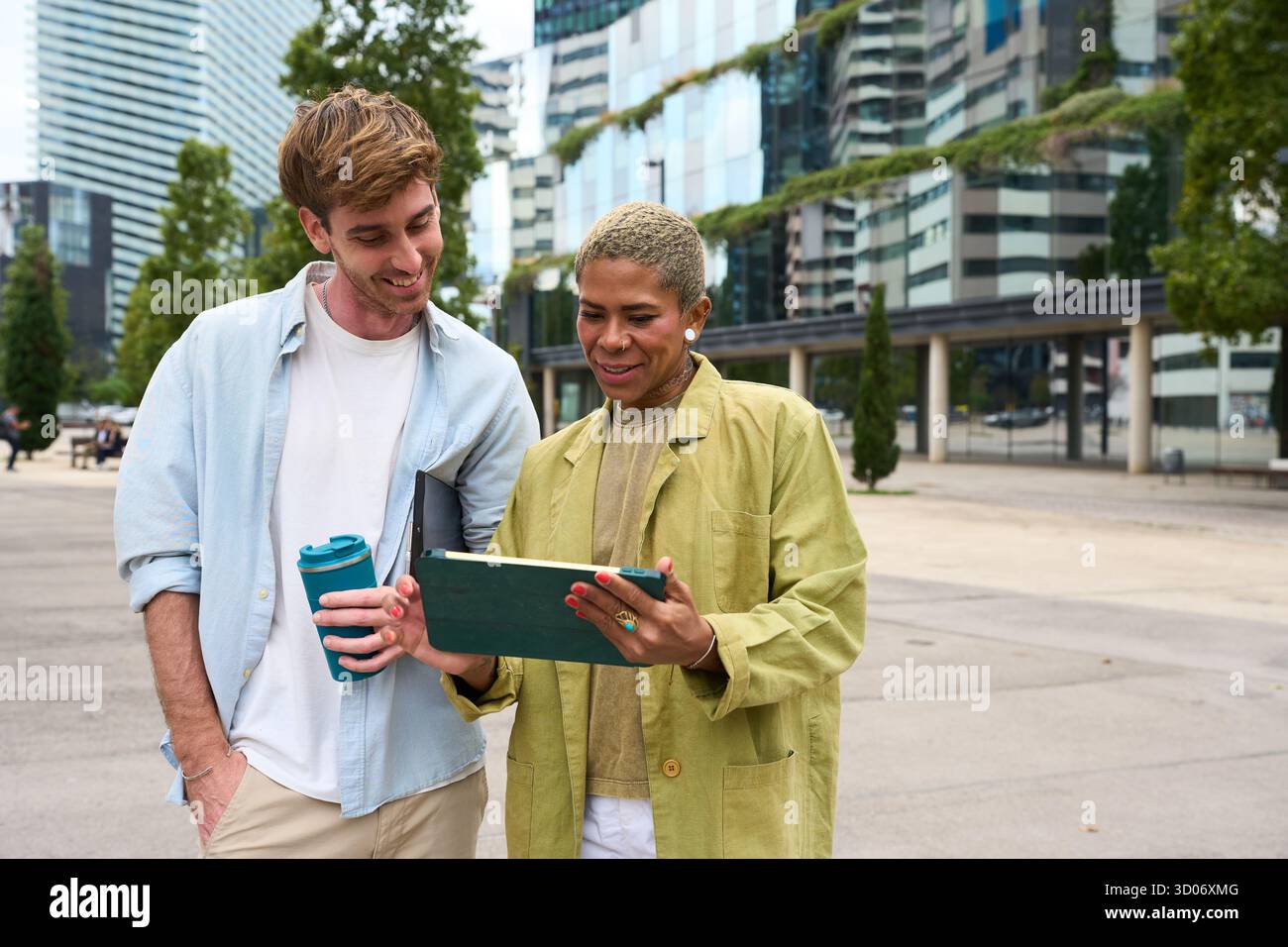 Diverse colleagues collaborating using digital tablet outdoors in city Stock Photo