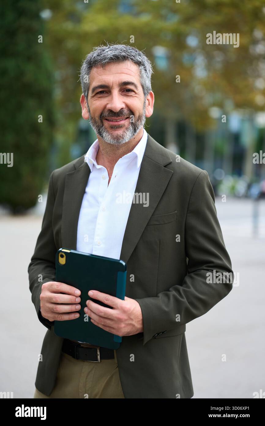Smiling mature businessman holding tablet in urban setting Stock Photo