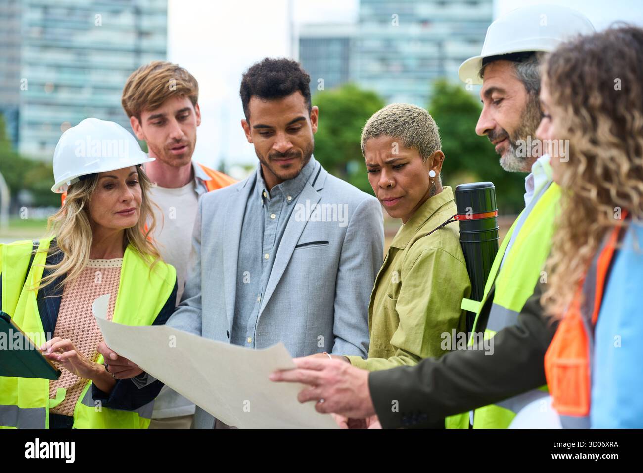 Diverse construction team reviewing blueprint on site Stock Photo