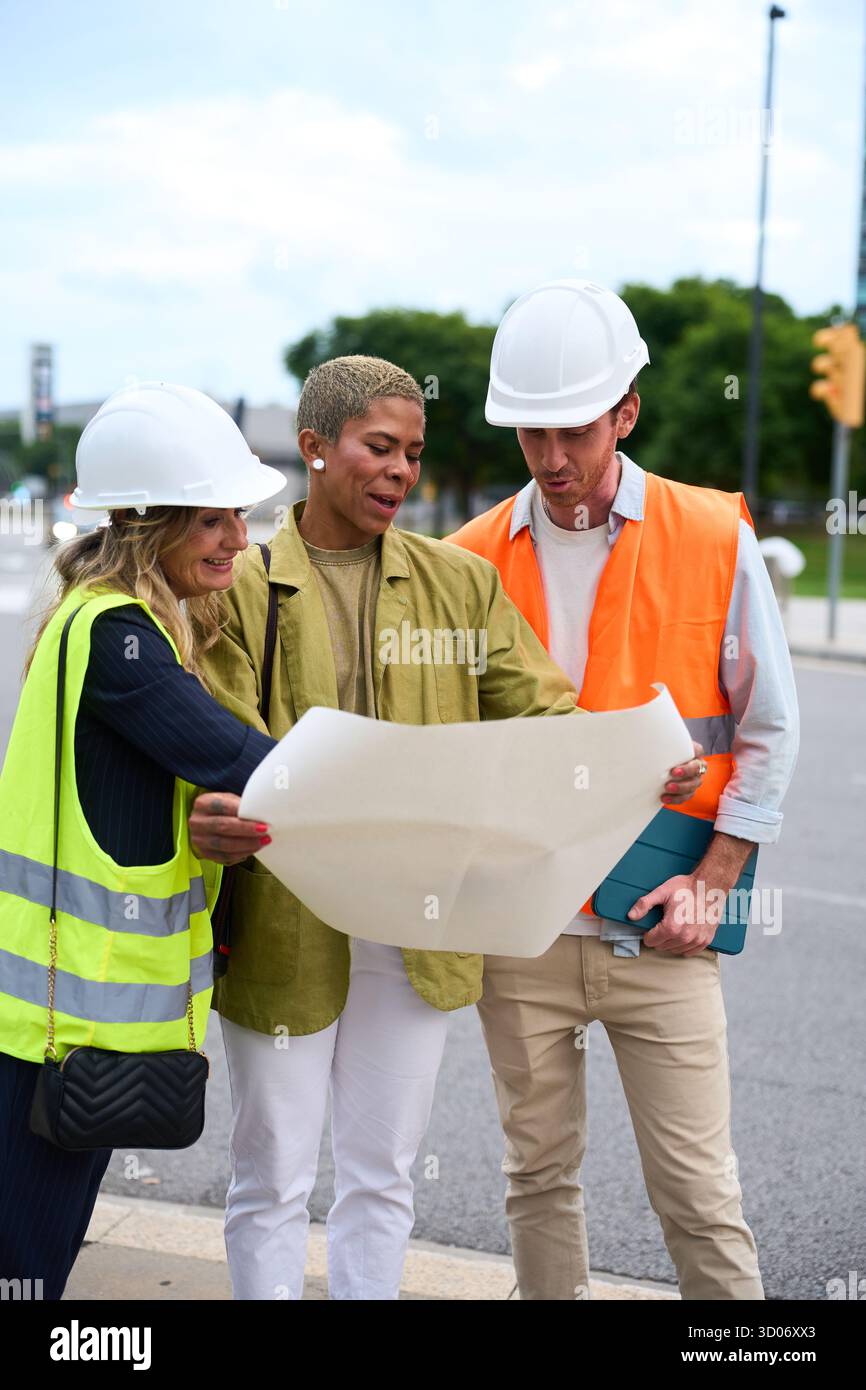 Diverse construction team reviewing blueprint on site Stock Photo