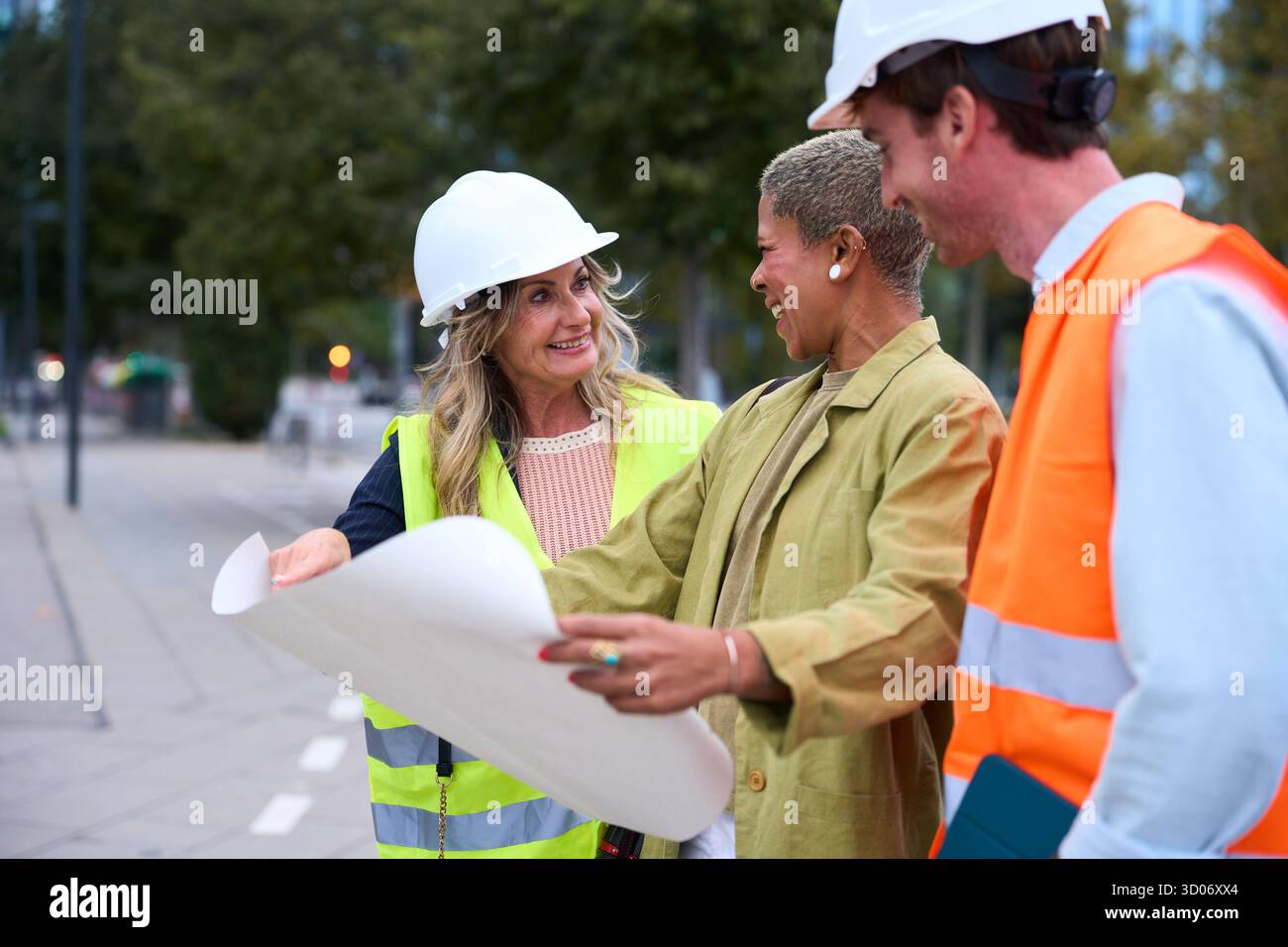 Diverse construction engineers team discussing blueprint outdoors Stock Photo