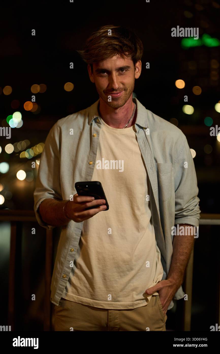 Young man smiling and using smartphone at night Stock Photo