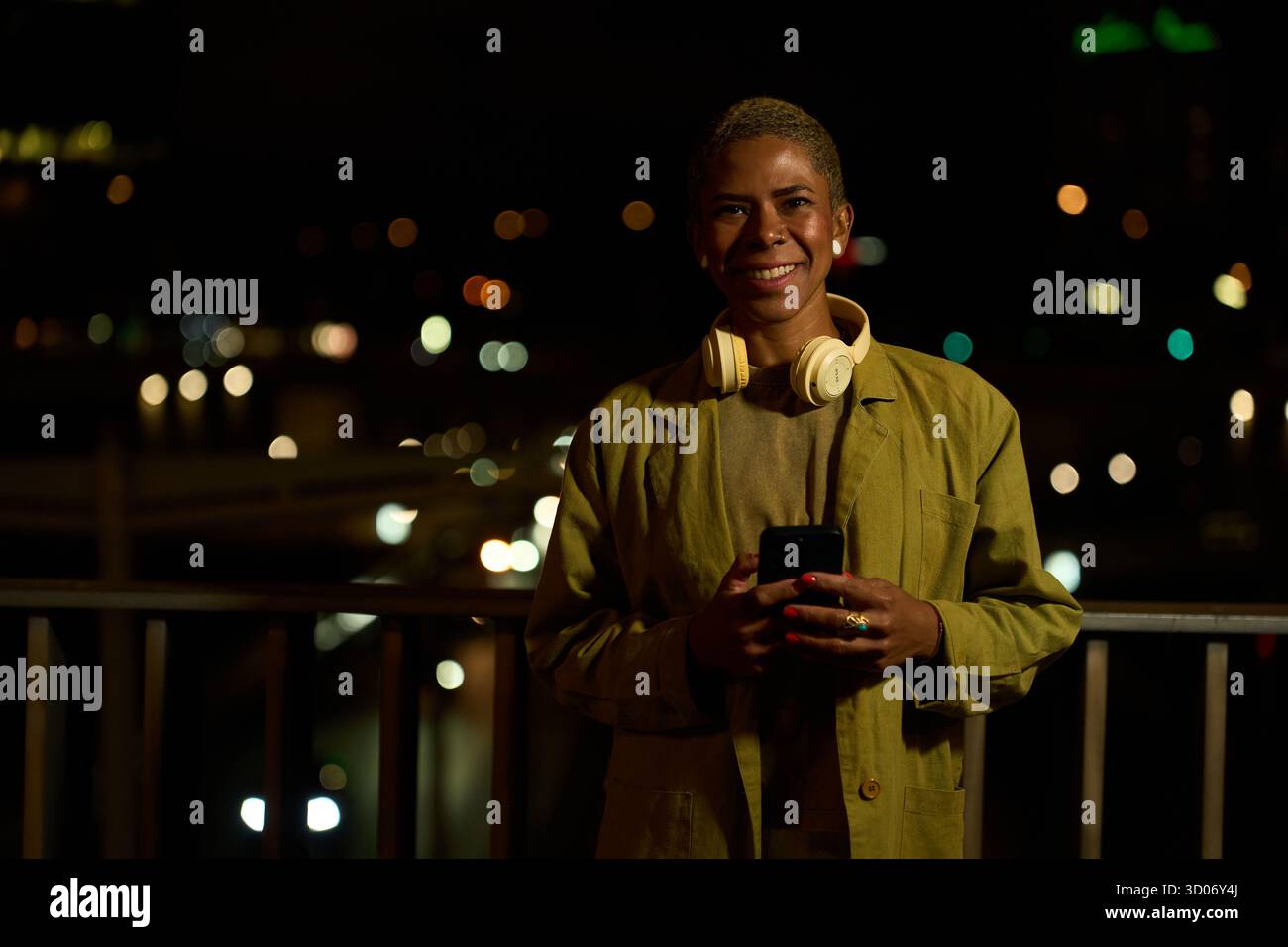 Young woman smiling using smartphone at night city Stock Photo
