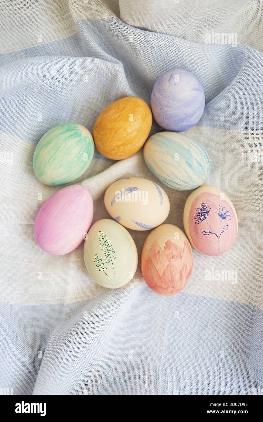 Painted bright and multi-colored Easter eggs on the background of a linen tablecloth, eggs painted with watercolors Stock Photo