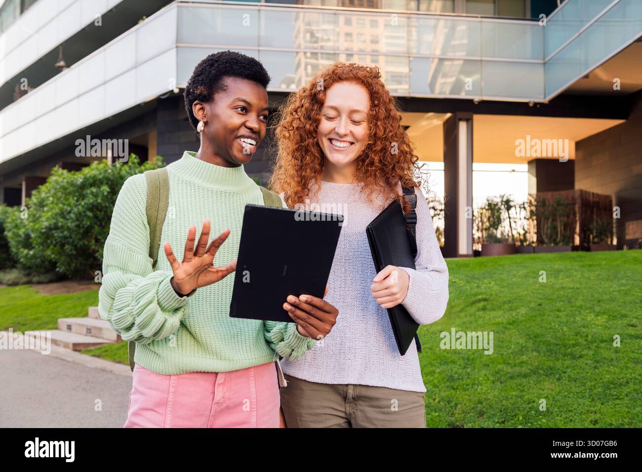 two young women smiling while using a tablet Stock Photo
