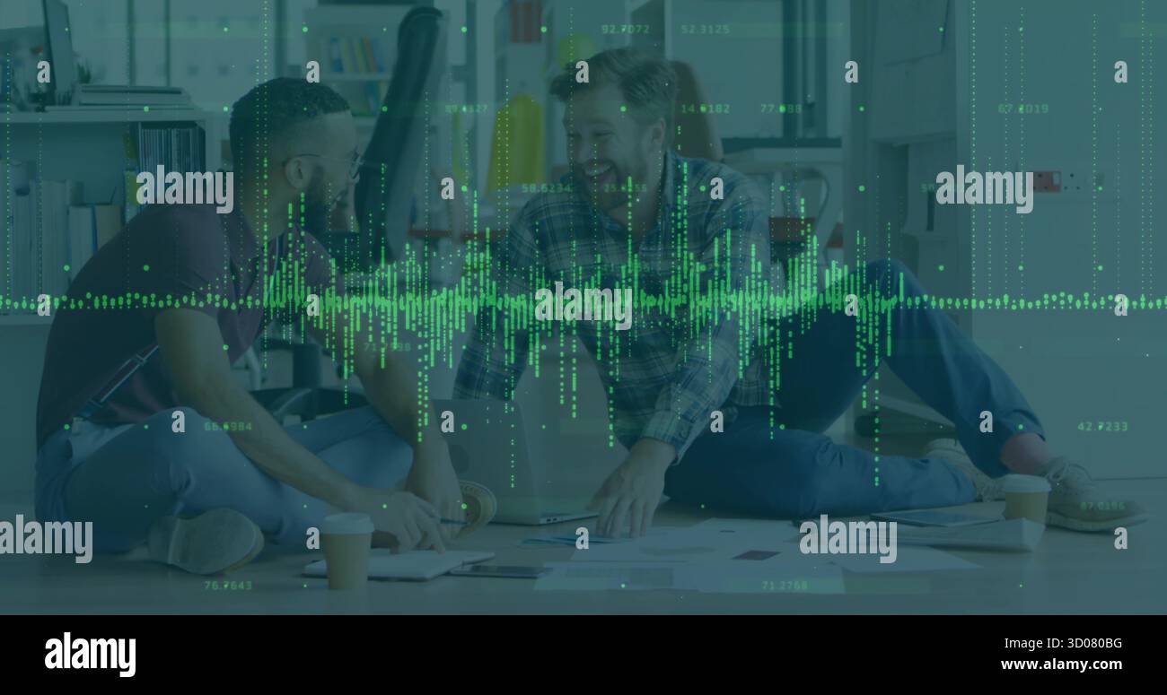 Collaborating men in shirts, jeans working on laptop in office lounge, with papers waveform overlay Stock Photo