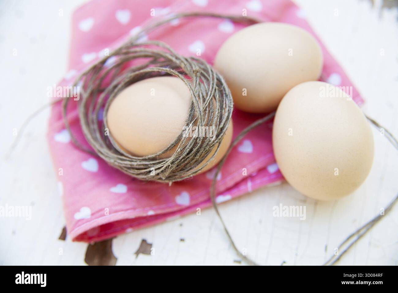 Three eggs on the table on a rose napkin Stock Photo