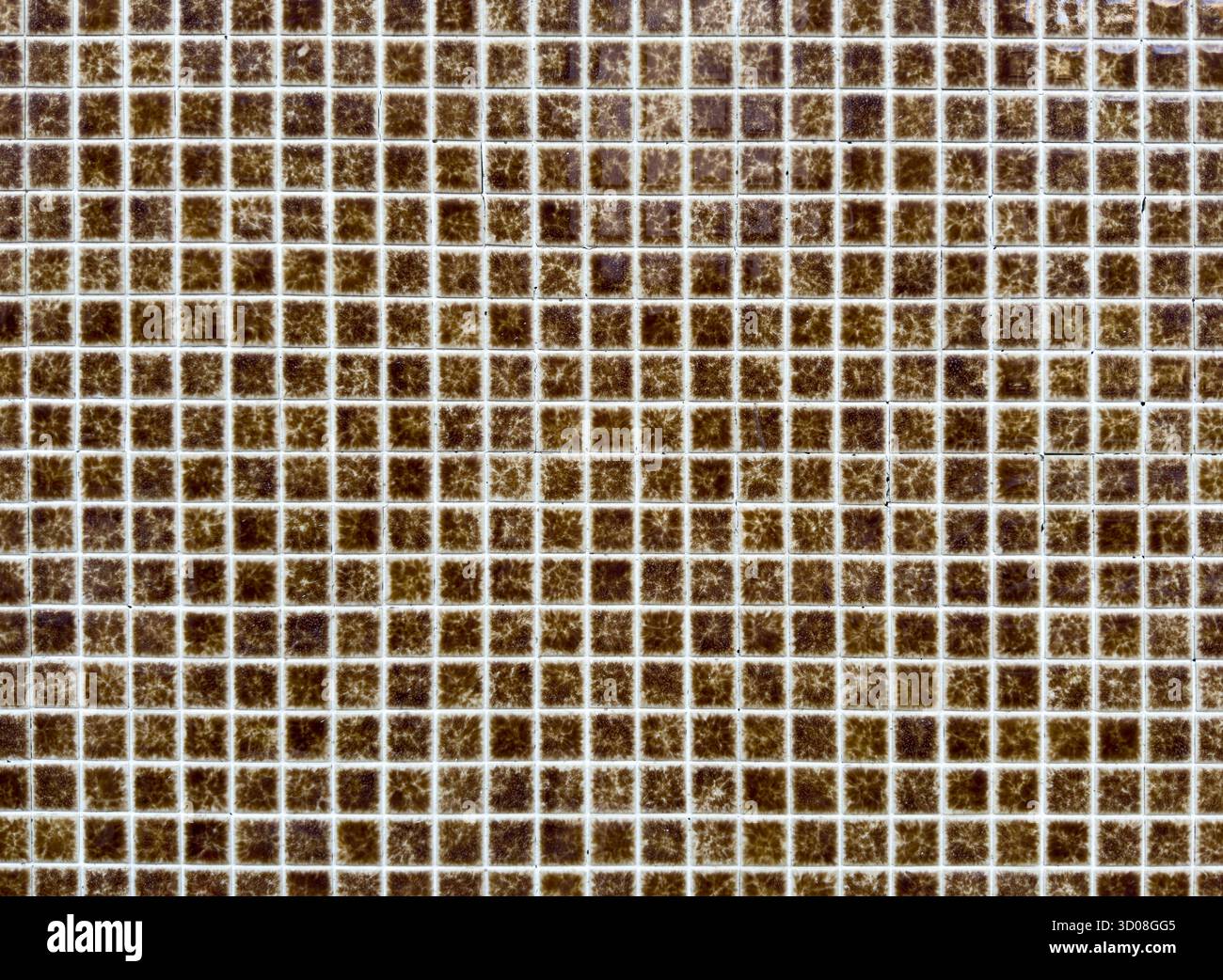 Mosaic tile pattern forms geometric grid. Small square ceramic brown tiles create textured decorative surface with symmetrical abstract design, classi Stock Photo