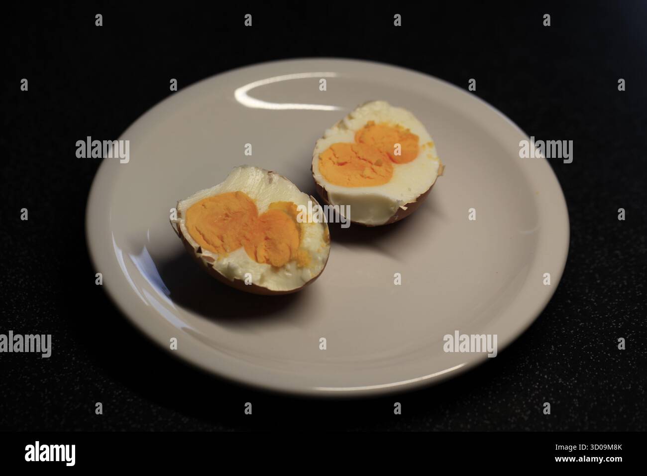 view from above on a rare half boiled chicken egg with double yolk on a white plate. Photo by Willy Matheisl Stock Photo