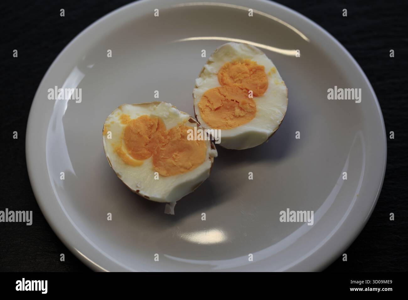 view from above on a rare half boiled chicken egg with double yolk on a white plate. Photo by Willy Matheisl Stock Photo