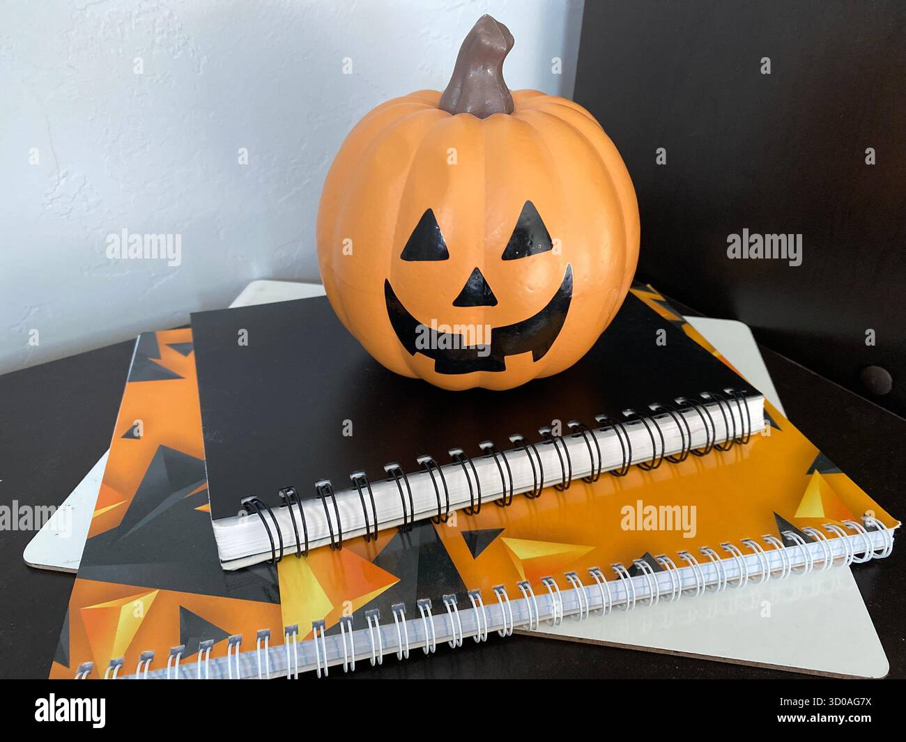 Halloween composition including a pumpkin and notebooks, orange, black and white colors - Smartphone Captured Stock Image