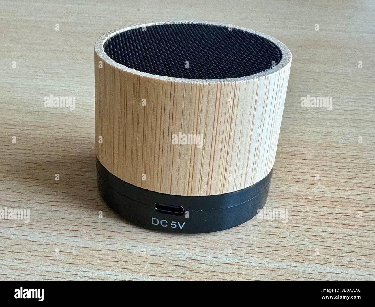 Bamboo Bluetooth speaker on wooden surface showing DC 5V charging port. - Smartphone Captured Stock Image