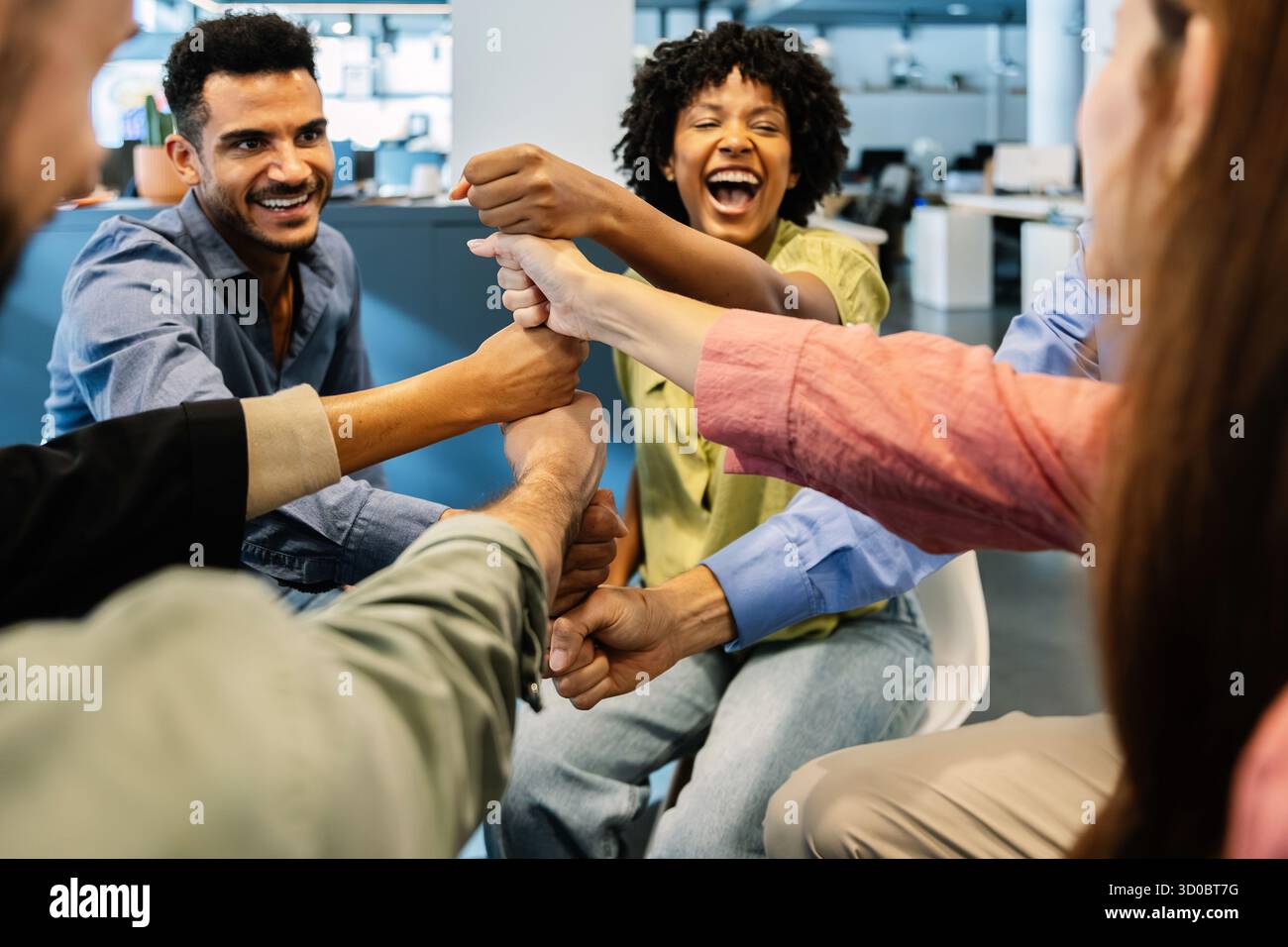 Diverse business team smiling while stacking fists together at office Stock Photo