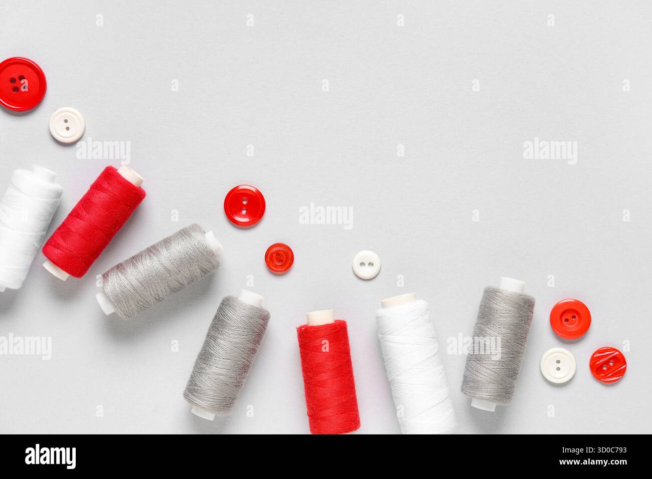 Thread spools with buttons on grey background Stock Photo