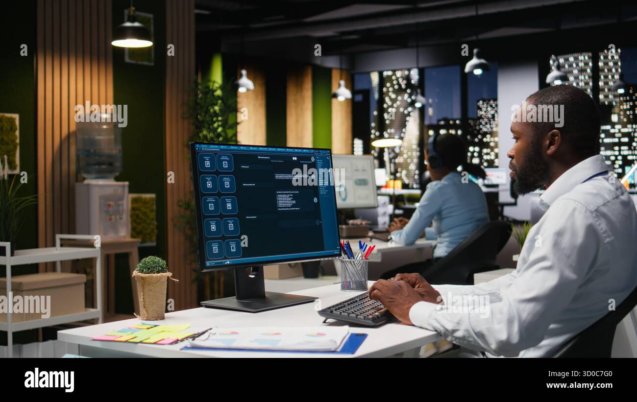 Black worker uses AI chatbot system at desktop for problem solving tasks, futuristic technology highlighting smart algorithms and machine learning. Communication and IT support. Stock Photo