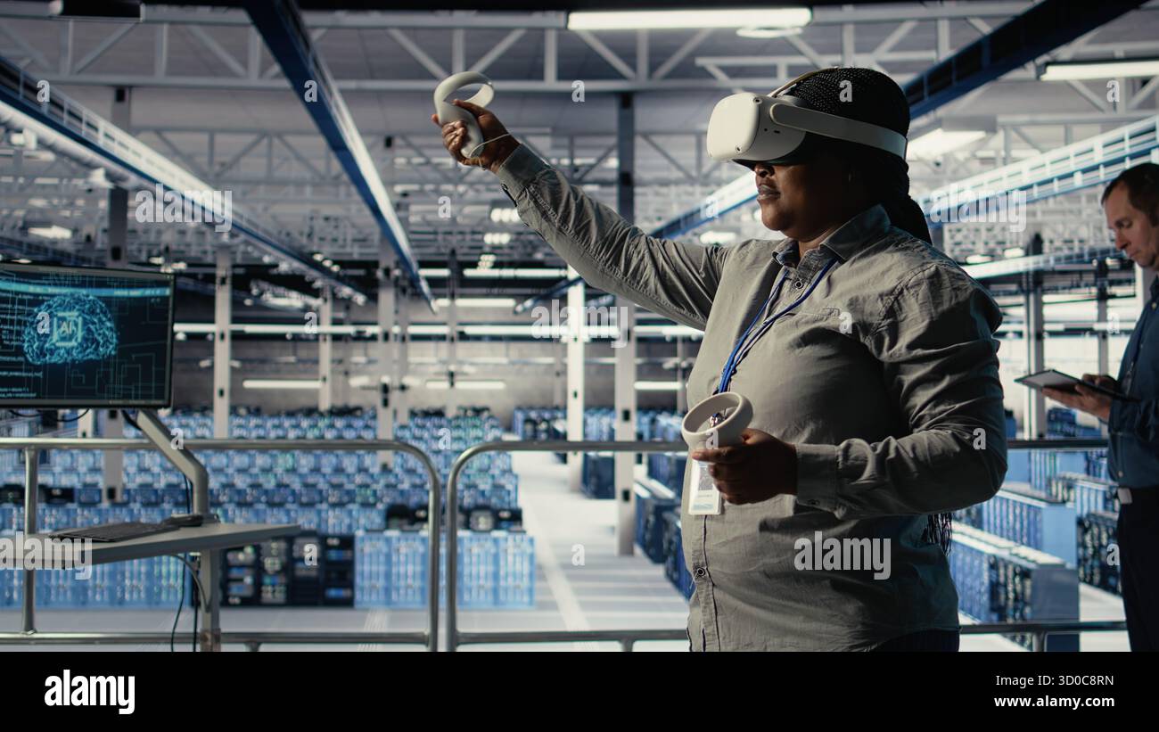 Software developer in server room wearing VR goggles optimizing deep learning systems handling tasks. African american woman in data center adjusts AI model parameters using virtual reality, camera A Stock Photo