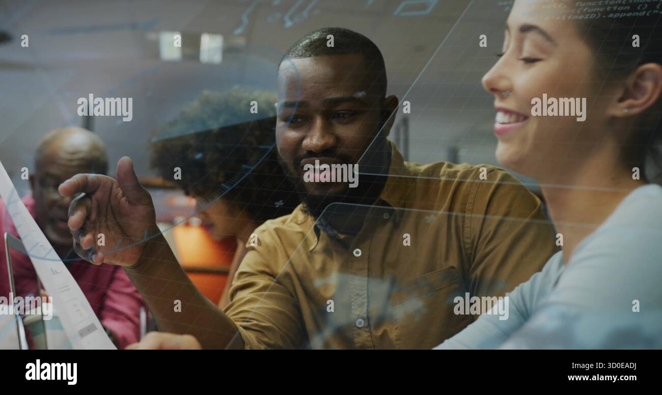 Pointing brown-shirted developer explaining interface code in open office, with glass partition Stock Photo