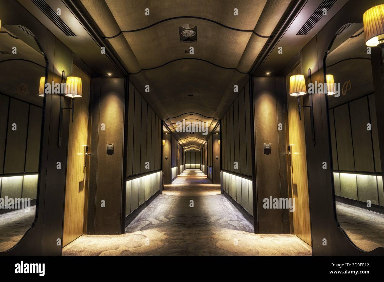 Looking straight into a long dark hotel corridor Stock Photo