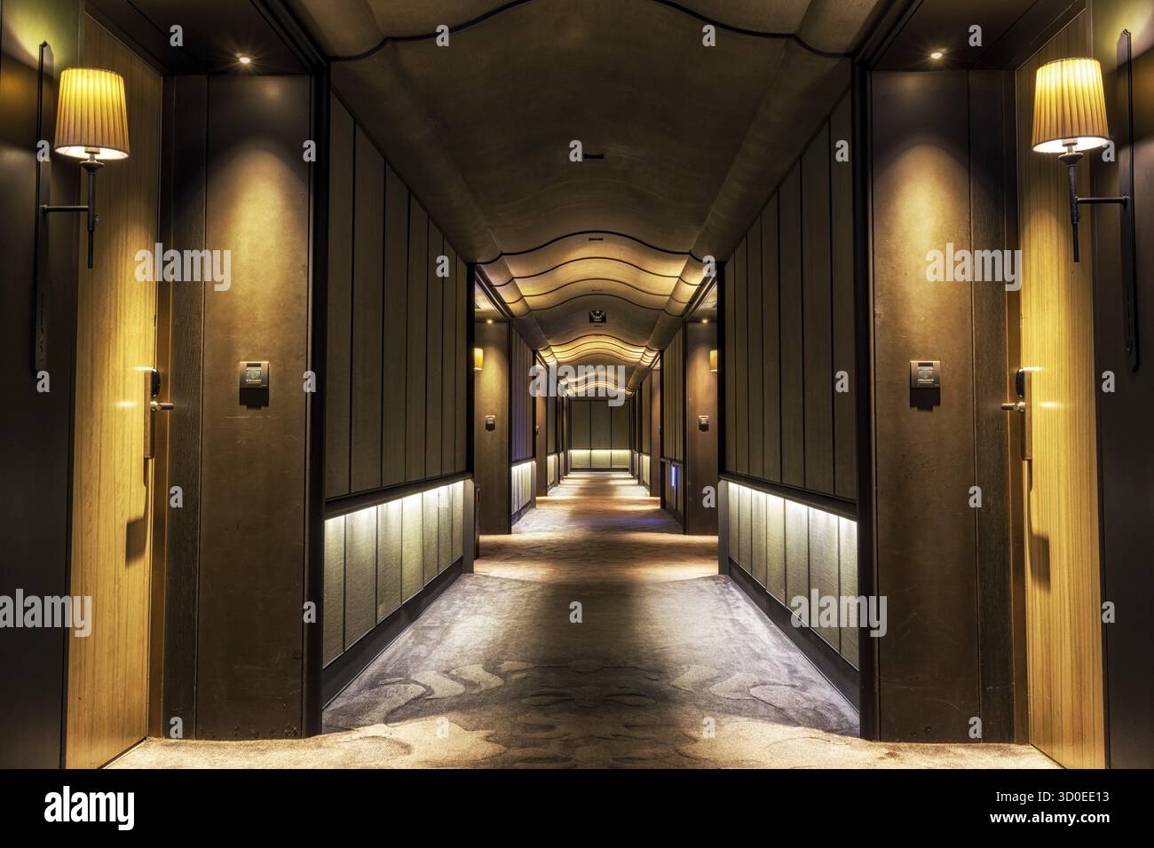 Looking straight into a long dark hotel corridor Stock Photo