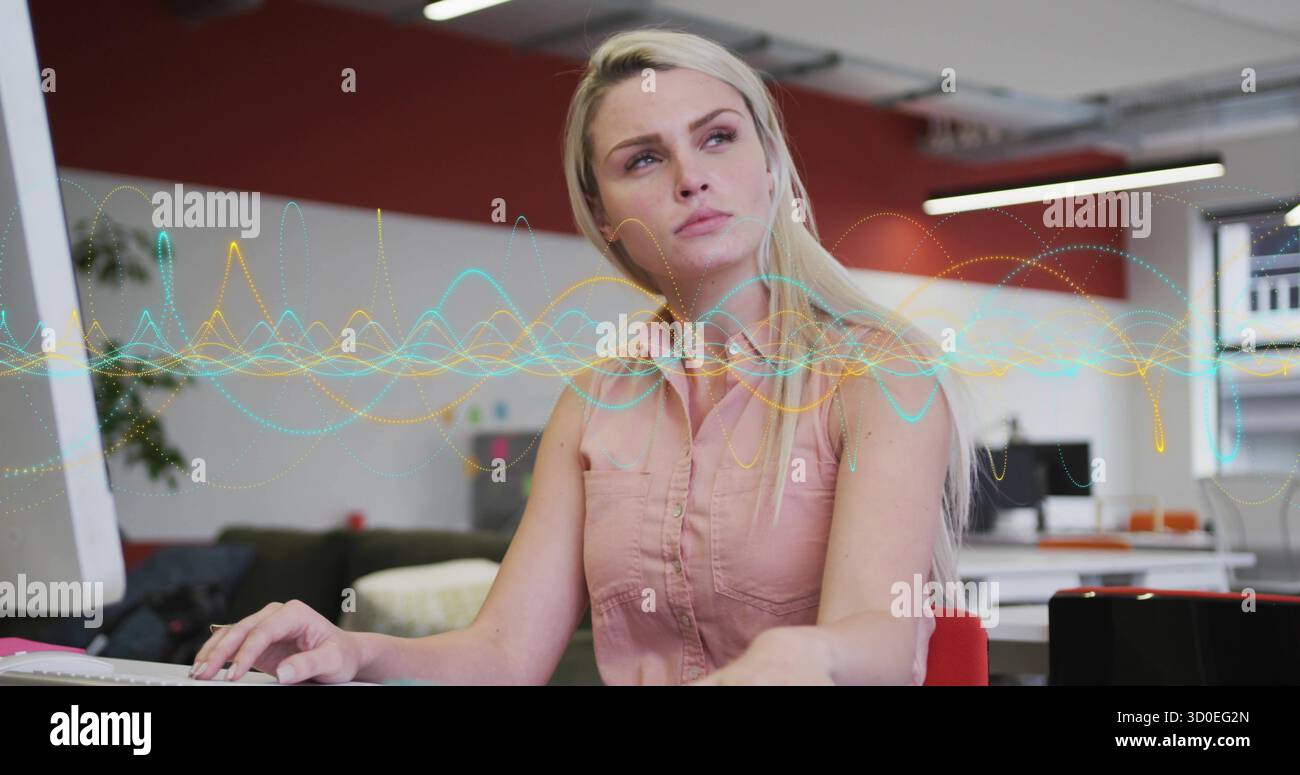 Typing woman developer entering code on keyboard at desk in open-plan office, with waveform overlay Stock Photo
