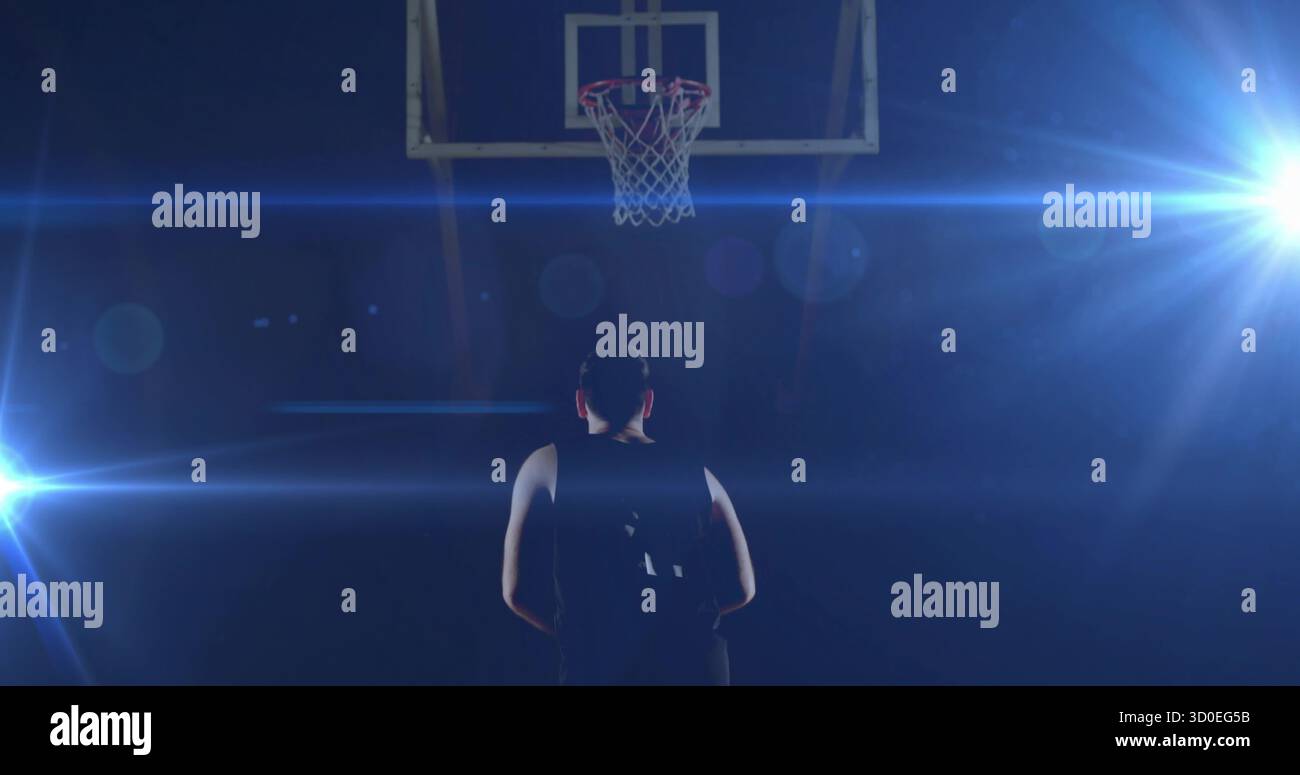 Standing athlete wearing jersey under basketball hoop on court with ...