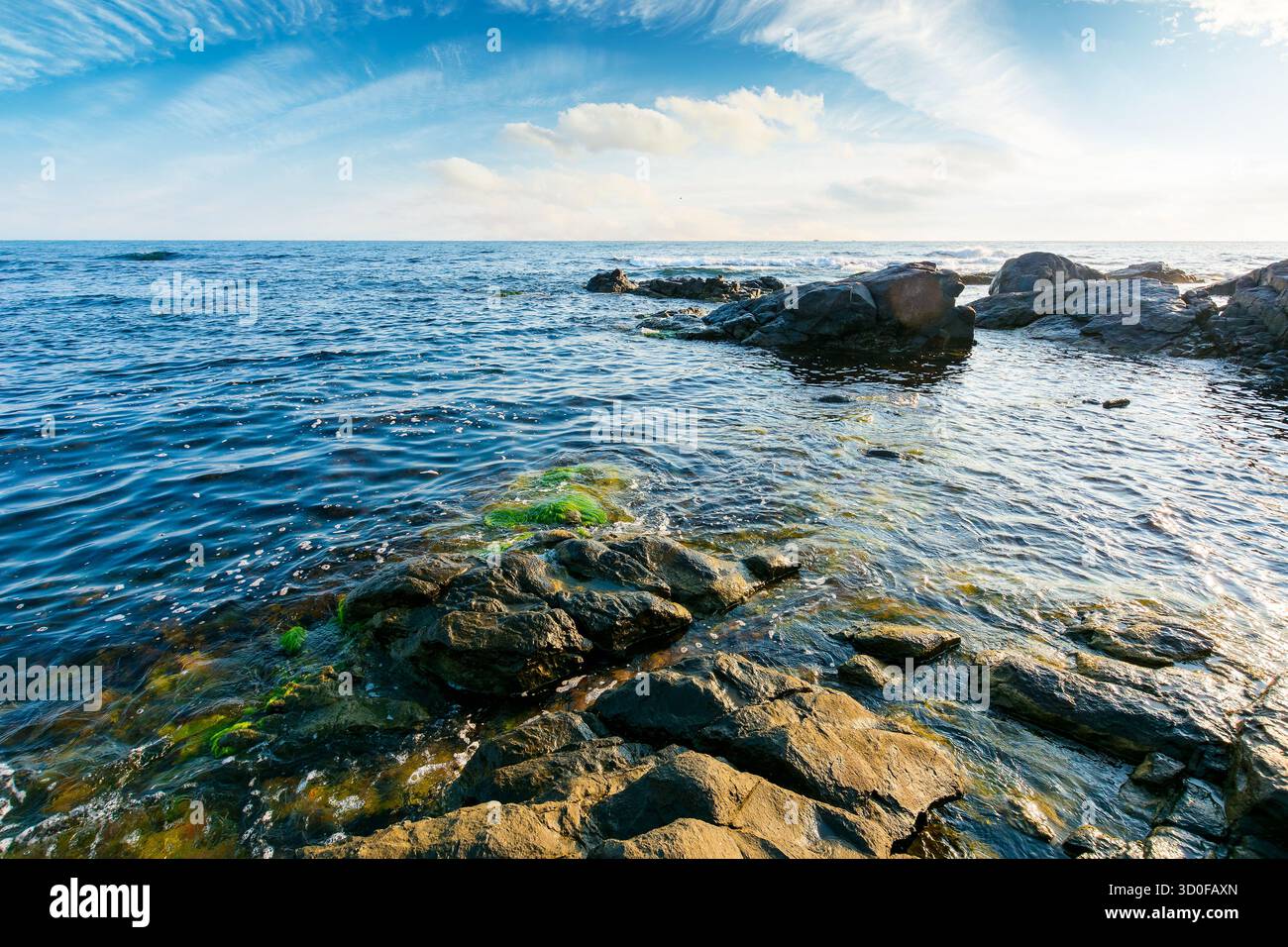 weekend on a rocky beach at the black sea under open blue sky. beautiful coastline of bulgaria in summer. seascape scenery on a bright morning with cl Stock Photo