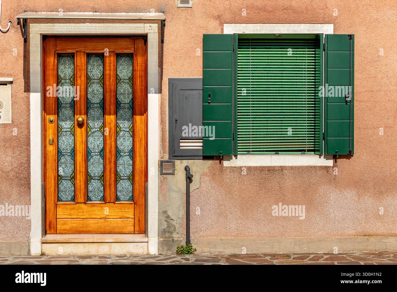 A wooden door and a window with green wooden shutters and green Venetian blinds in a street in the Santa Croce sestiere of Venice,Italy Stock Photo