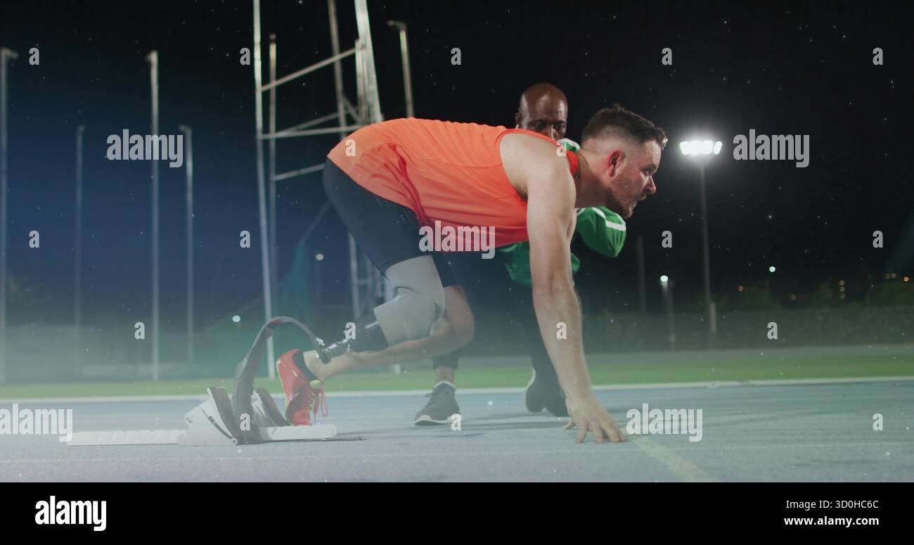 Crouching athlete with prosthetic blade waiting on floodlit night track ...