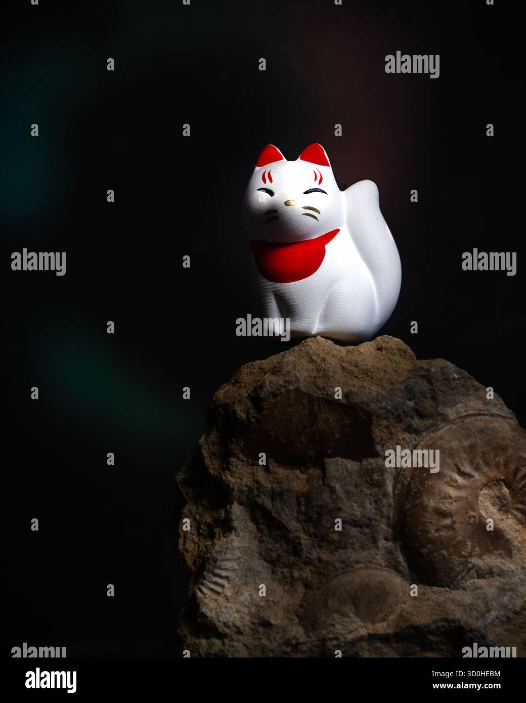 Japanese fox charm on a rock containing ammonites - Stock Image
